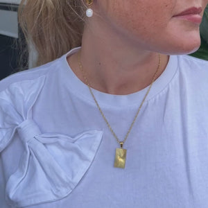 Sun Halskæde vist i bevægelse med fokus på solvedhænget og den gyldne finish.
