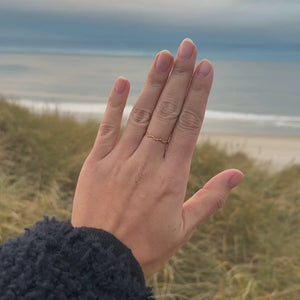 Hamret Tynd Ring vist i bevægelse med fokus på den hamrede overflade og den gyldne finish.